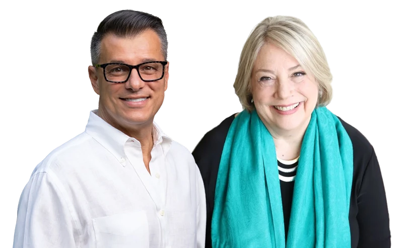 Two adults, one man wearing glasses and a white shirt, and one woman with a turquoise scarf and striped top, standing side by side and smiling at the camera.